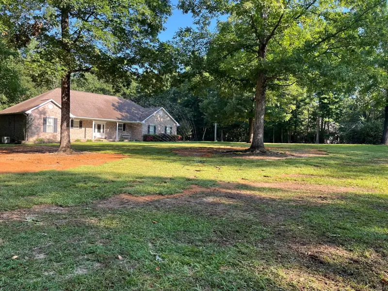 Open front yard of a brick home after several trees were taken down and the ground smoothed