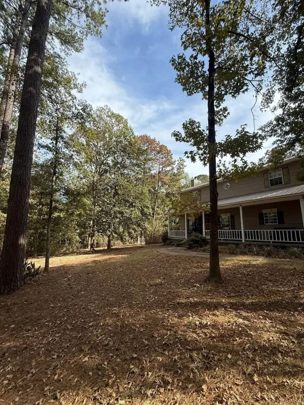 Two-story home with a raked yard under the trees after cleanup and debris haul-off